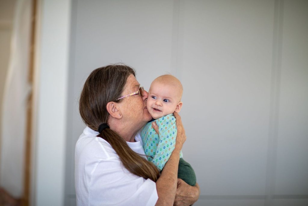 A grandmother holding and kissing her grandchild.