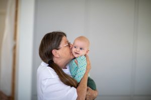A grandmother holding and kissing her grandchild tickled pink.