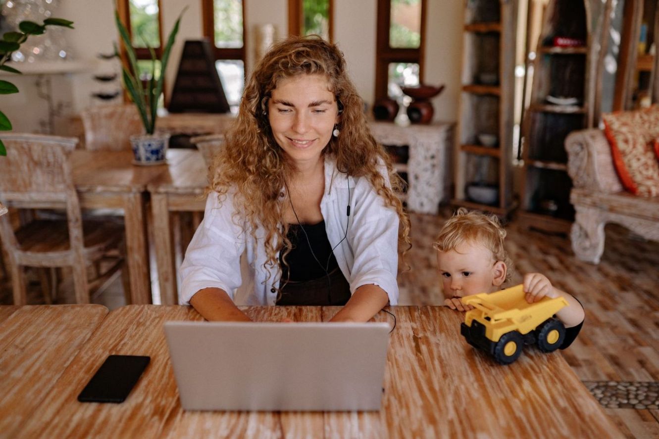 A mother working at home while her child plays.